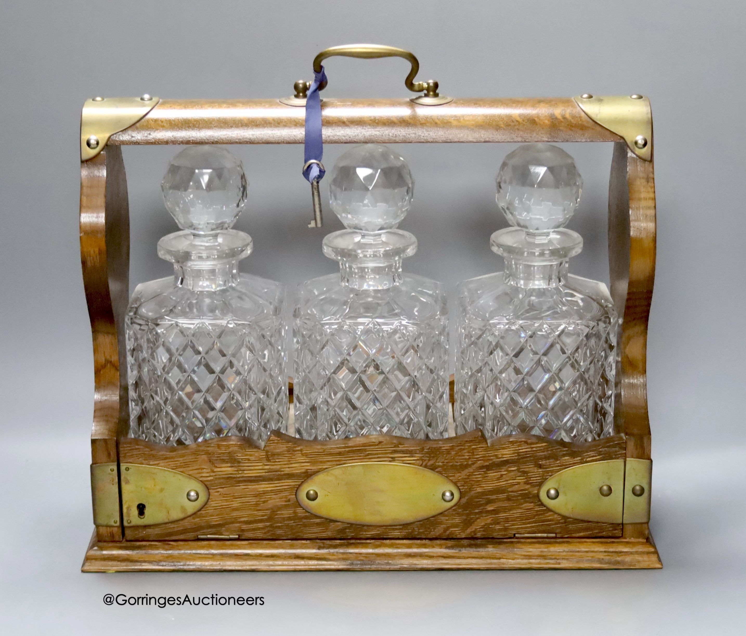 An oak and brass mounted three bottled tantalus, 36 x 31cm